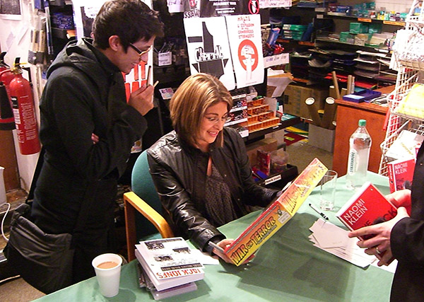 Naomi Klein and her assistant study the box of War on Terror, the boardgame